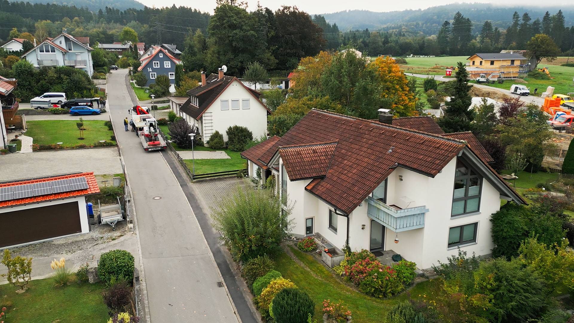 Thumbnail. Wohnhaus mit drei Menschen die davor laufen. Luftansicht
