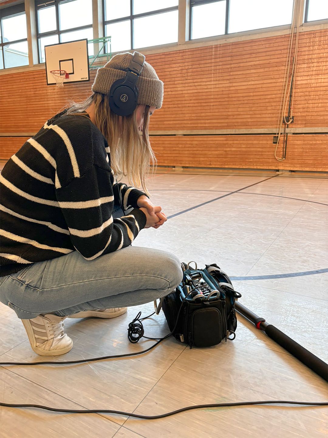 Ton-Frau bei der Arbeit in einer Turnhalle. Sie stellt etwas an einem Gerät ein.