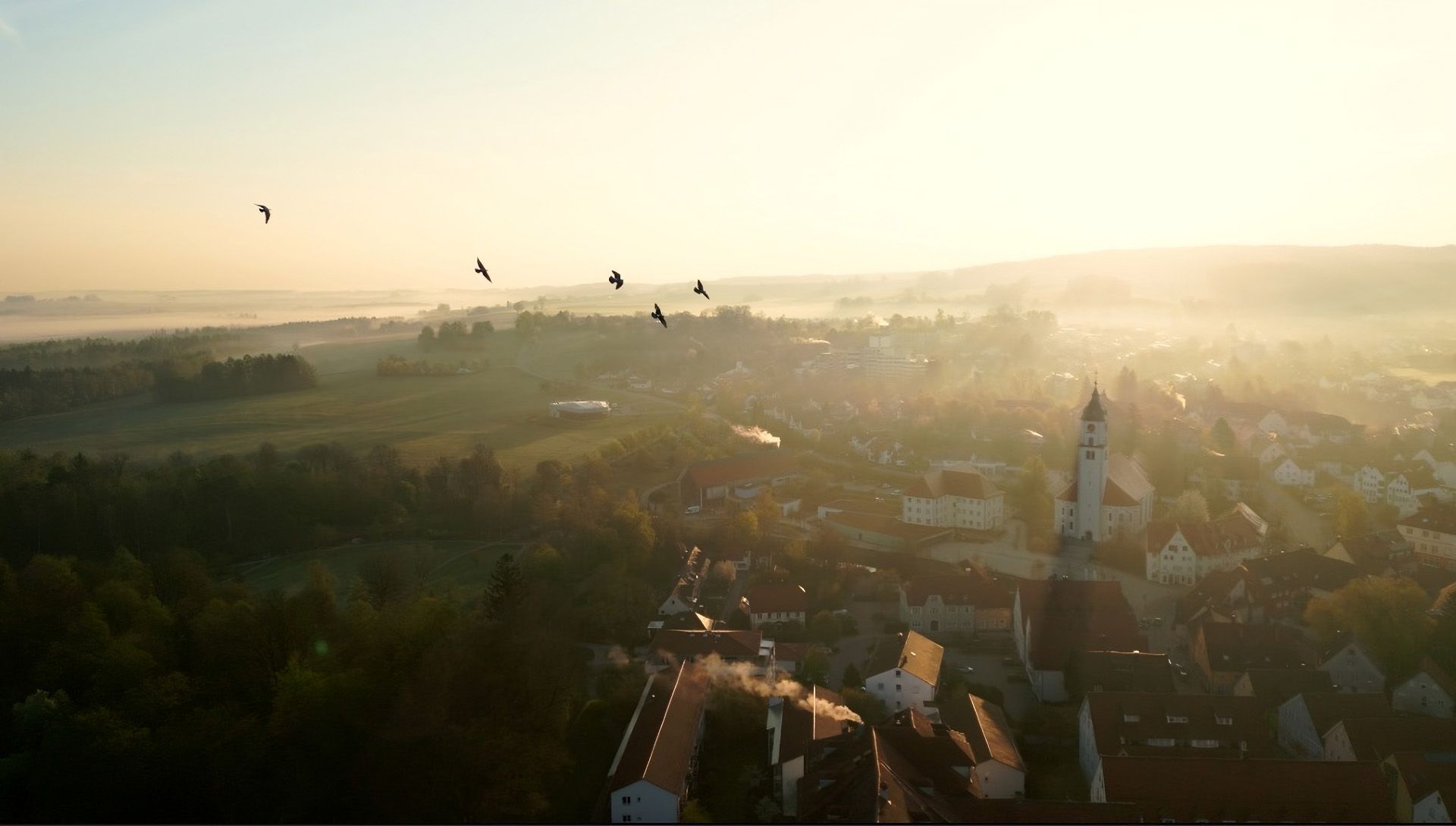Thumbnail - Drohnenaufnahme von der Stadt Bad Wurzach im Sonnenaufgang bei Nebel
